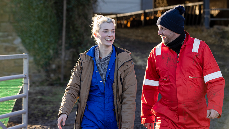 Man and woman wearing overalls and high-visibility clothing on farm