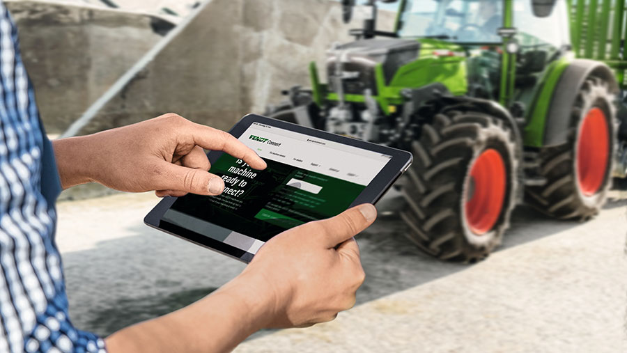Man on tablet showing display screen in front of tractor