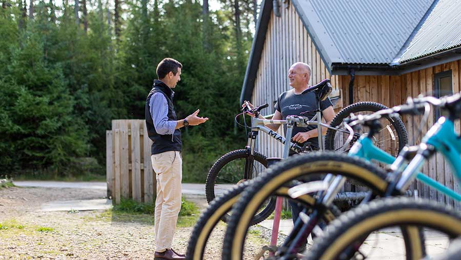 Two men discussing next to mounted bikes outside