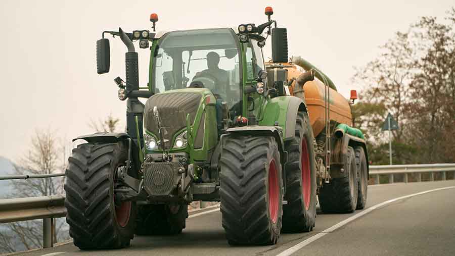 Green tractor travelling on a road