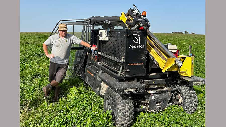 Man stood next to soil sampling machine in a field