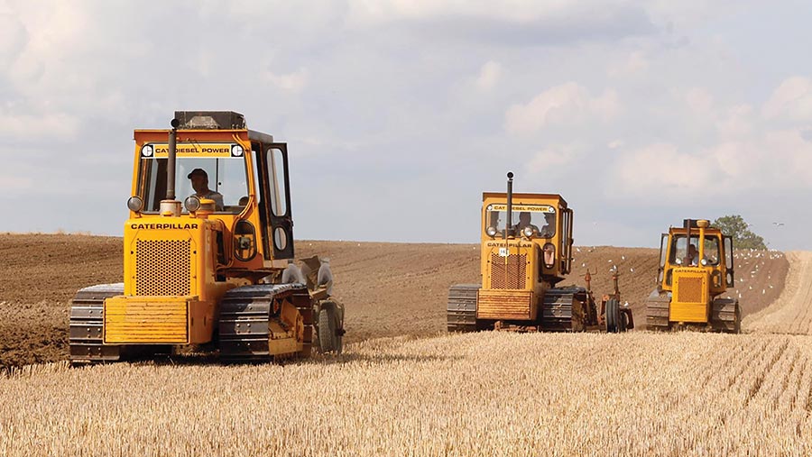 Three Caterpillar tractors in field