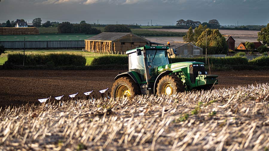 Period tractor and period plough in a field