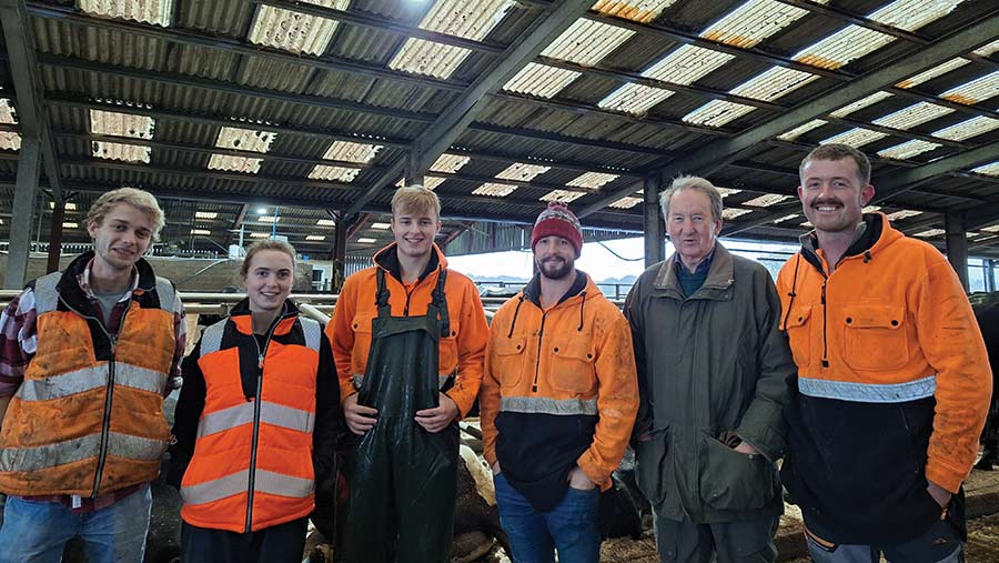 Farm team standing in a barn wearing high-visibility clothing