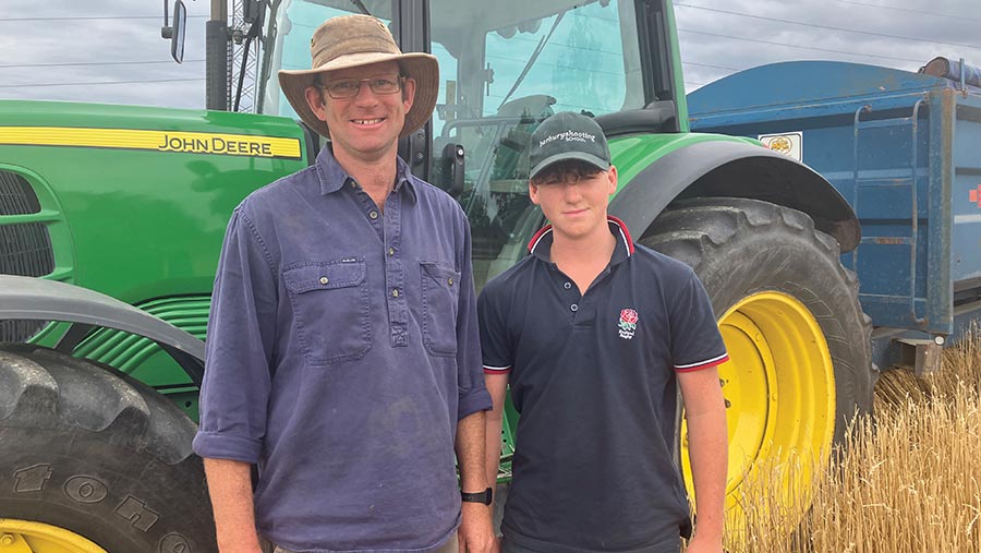 Farmer George Hosier and son Fred standing in front of a John Deere tractor
