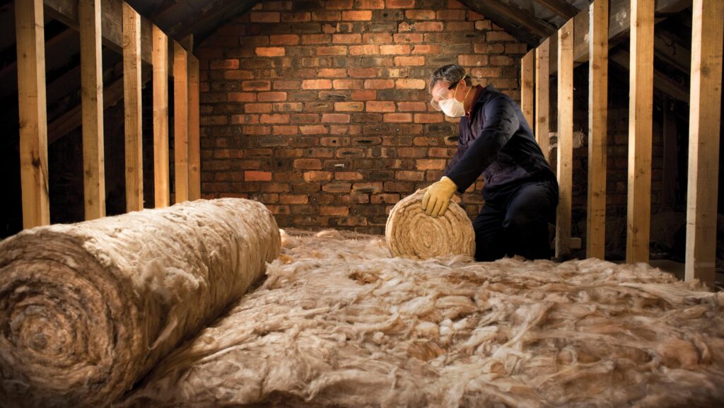 Worker laying insulation in loft