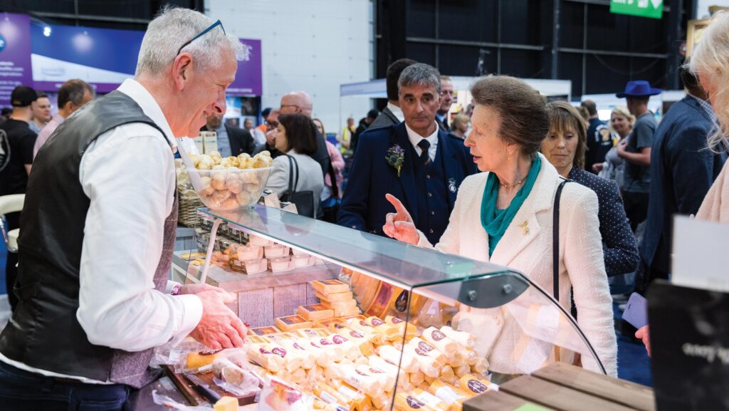 Two people talking over a display cabinet of cheese