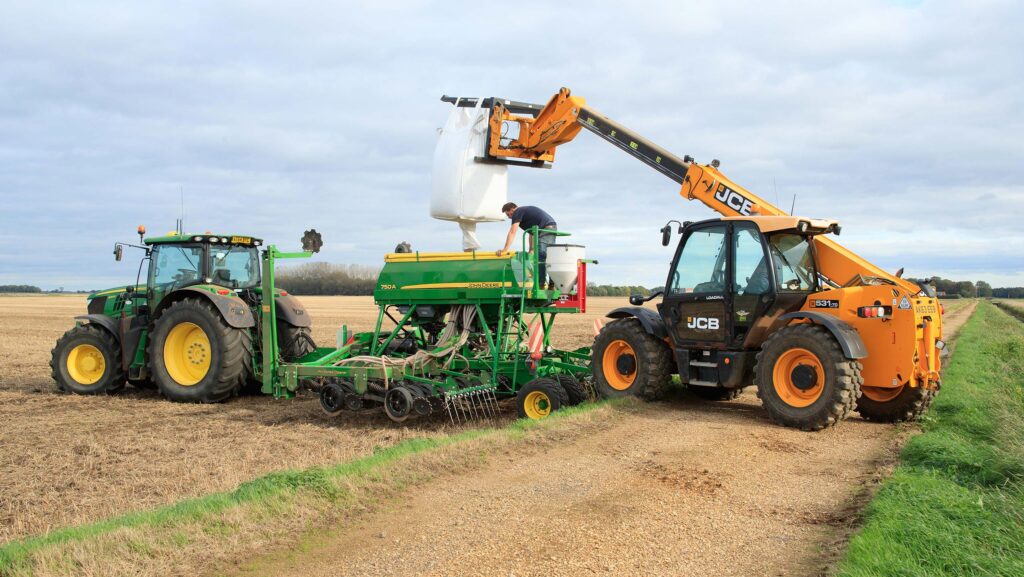 Telehandler loading a bag of seed into a drill