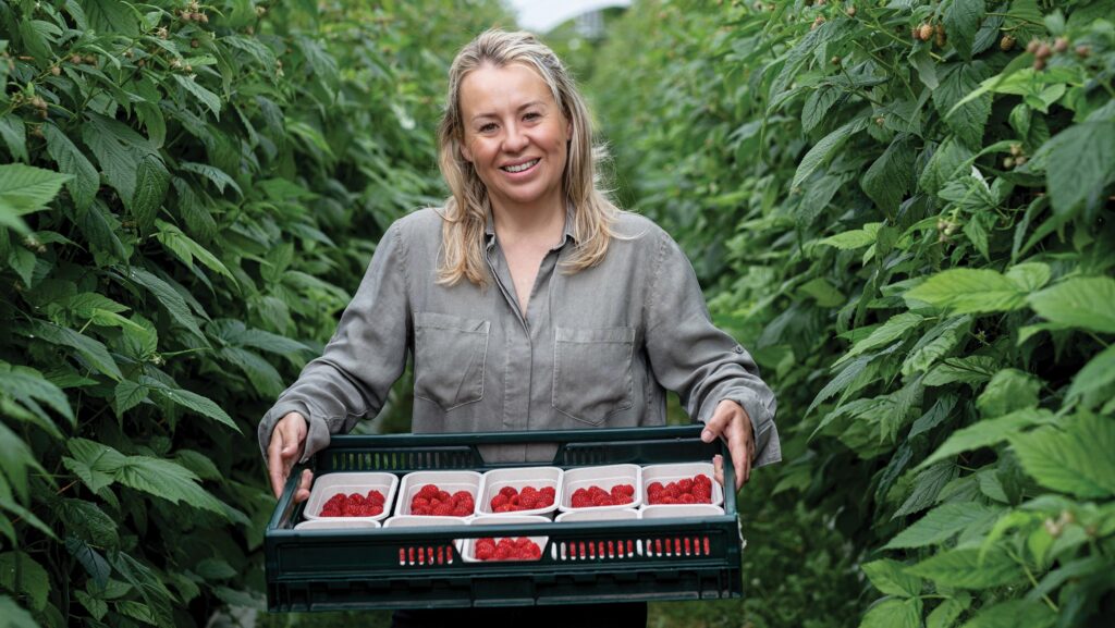 Annabel Makin-Jones in a polytunnel with a crate of strawberries