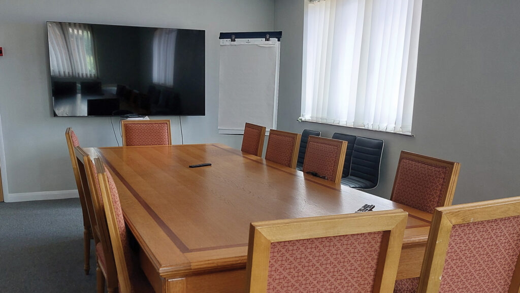 Board meeting room with a table, chairs, clipboard and TV