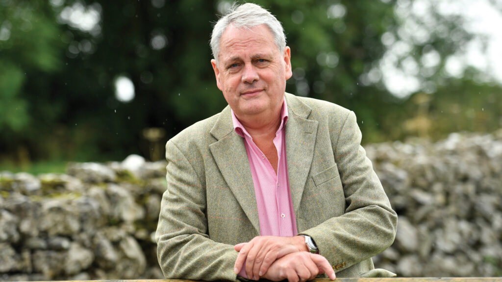 Alistair Mackintosh standing in front of a dry stone wall