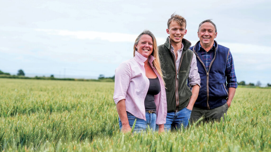 Three people standing in a green cereal crop