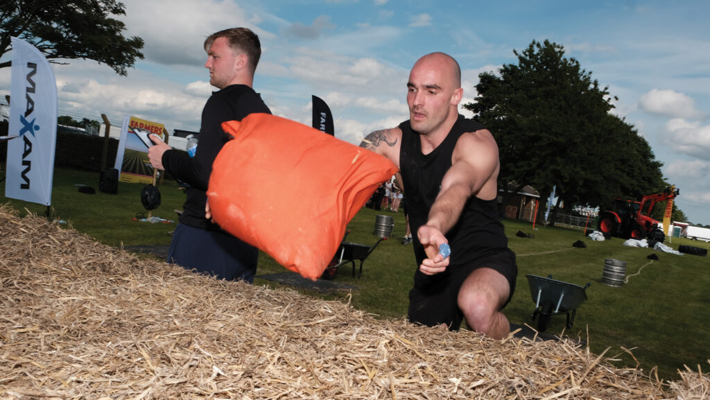 Edzus Smildzins throwing a weighted bag onto a bale