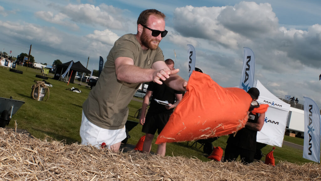 Harry Wallis throwing a weighted bag onto a bale