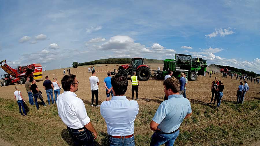 Small crowd of people watching an outdoor machinery demonstration