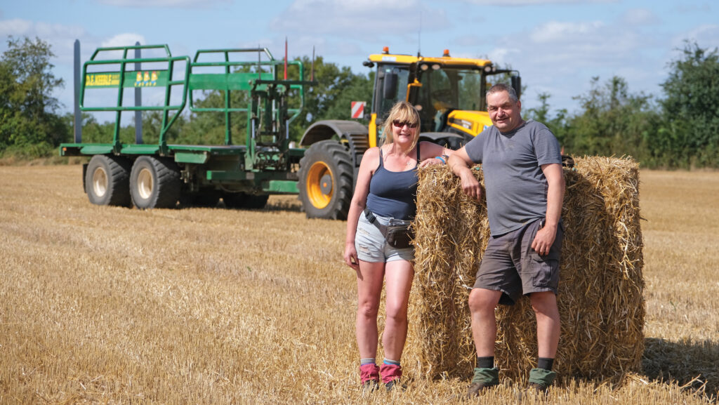 Couple standing in a field with bales