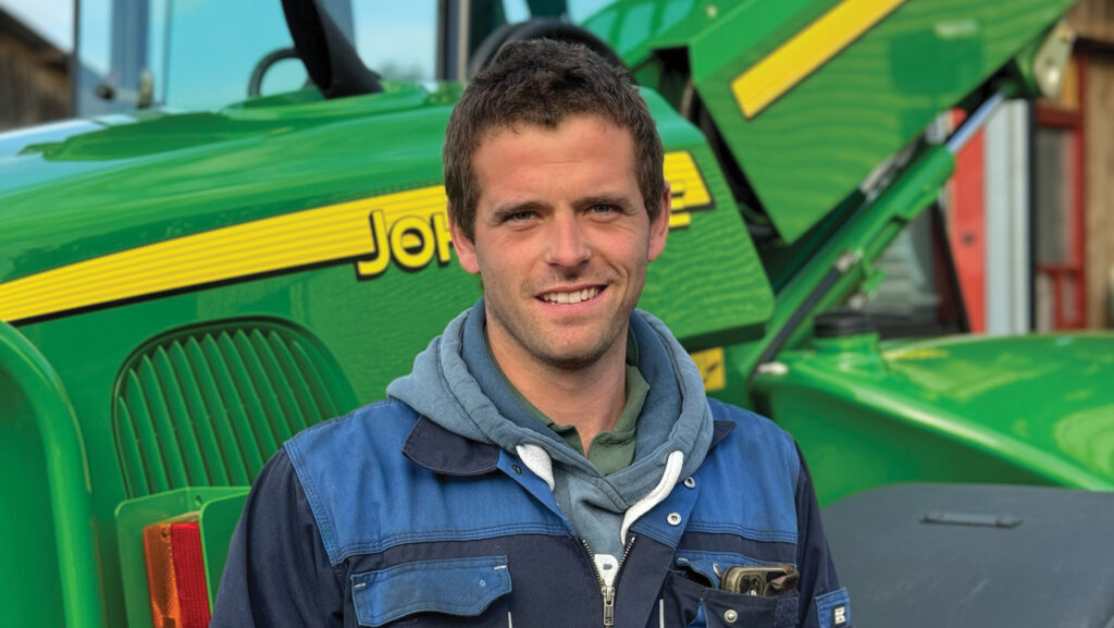 Marcus Tucker standing in front of John Deere machinery