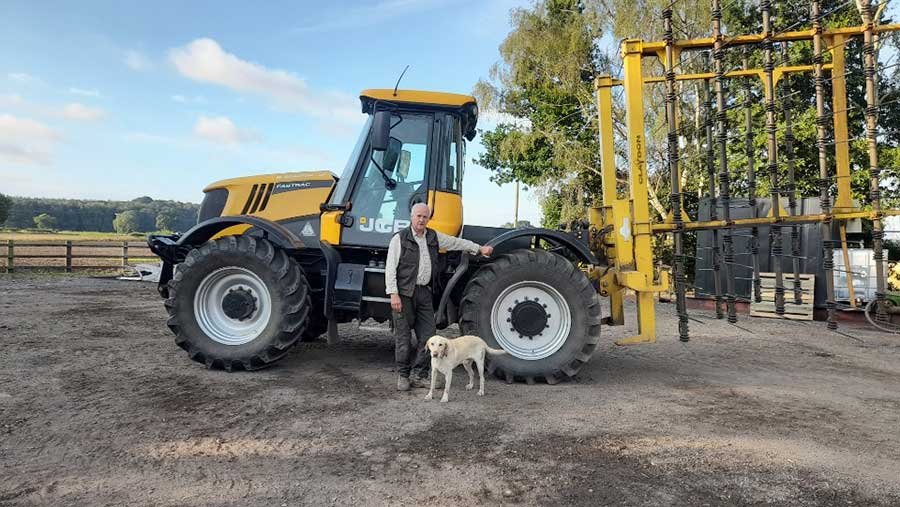 Robert Rooke standing next to a tractor and a dog in a farmyard