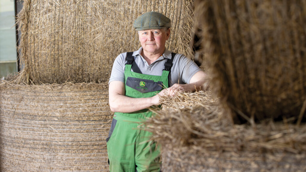 Farmer leaning on a bale in a shed