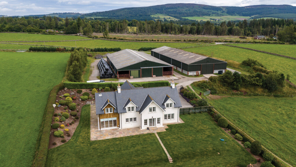 Aerial view of farm buildings and farmhouse surrounded by fields and trees