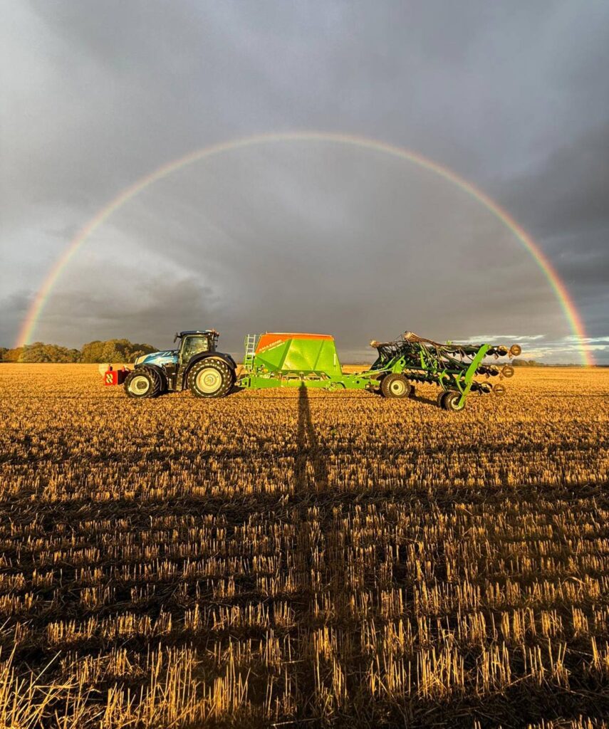 Drilling winter wheat in a field with a rainbow arching over the scene