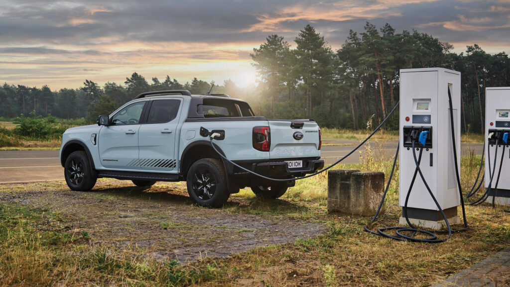 Ford Ranger PHEV pickup truck charging at a electric vehicle charging point near to woodland