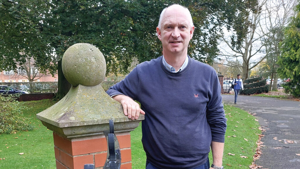 Man leaning on a brick gate pillar