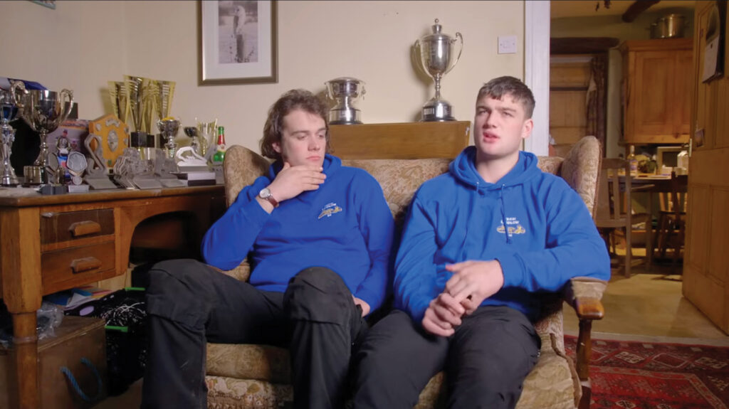 Two men sitting with trophies