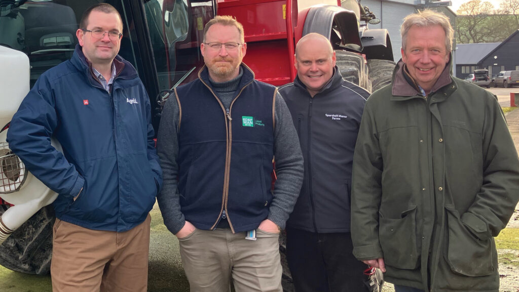 Four men standing by sprayer