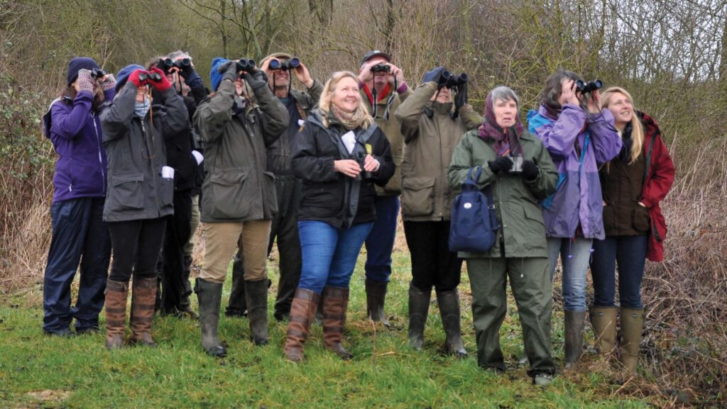 Group of people in outdoor clothing holding binoculars