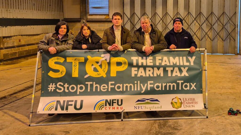 Four people stand with a large sign