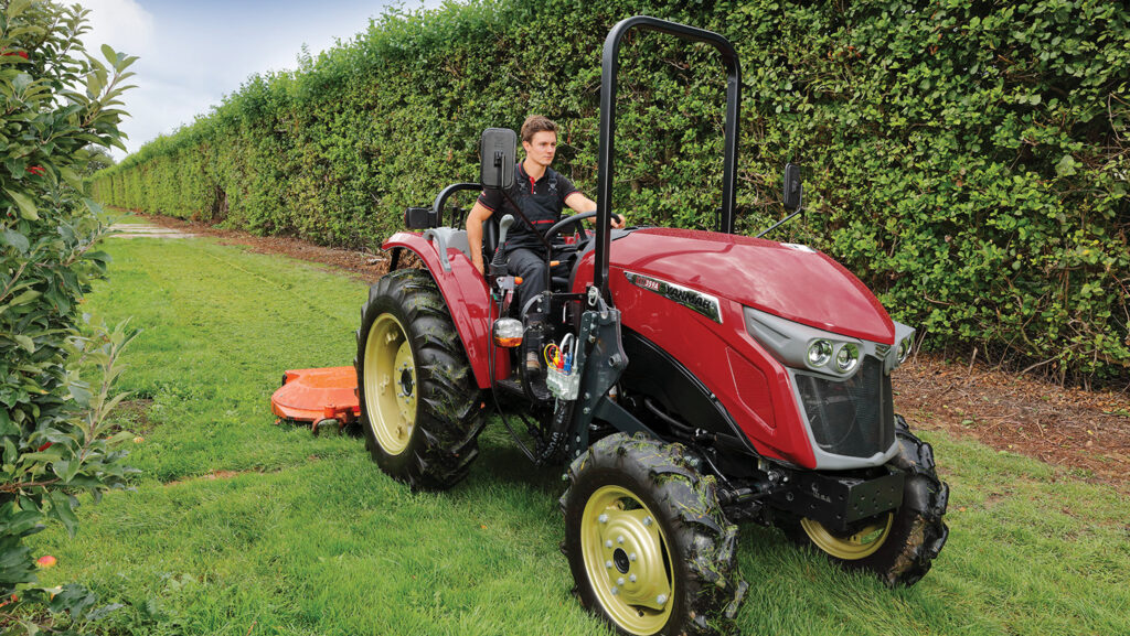 Worker mowing grass with a small tractor