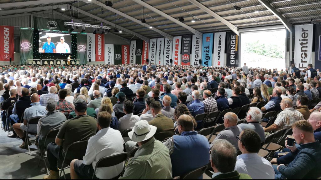 Large audience listening to a speaker inside a marquee