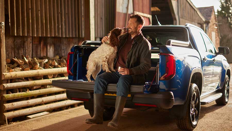 Man sat with dog on back of vehicle