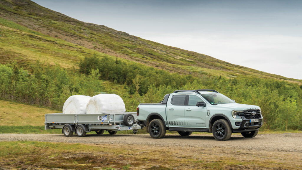 Pickup pulling a trailer with round bales