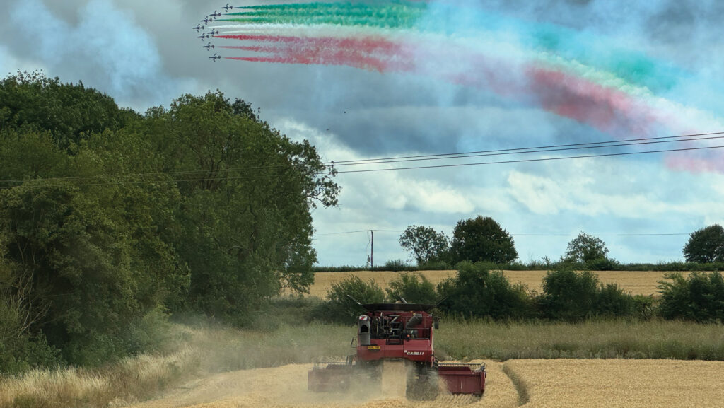 Red Arrows planes flying over wheat field during harvest