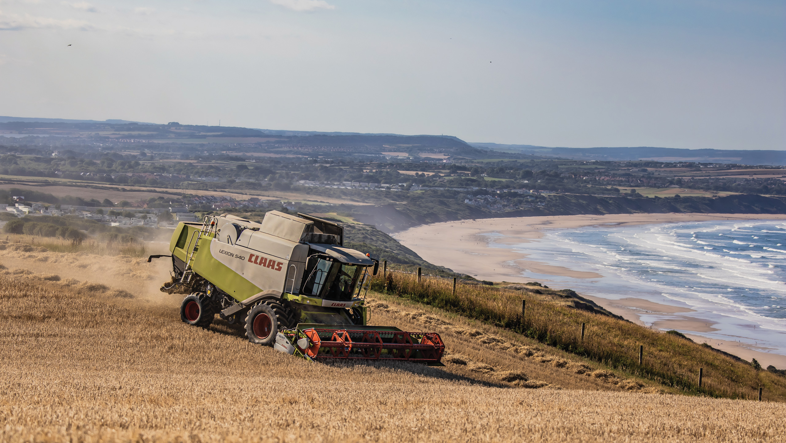 Class combine cutting barley against a backdrop of the East Yorkshire coast