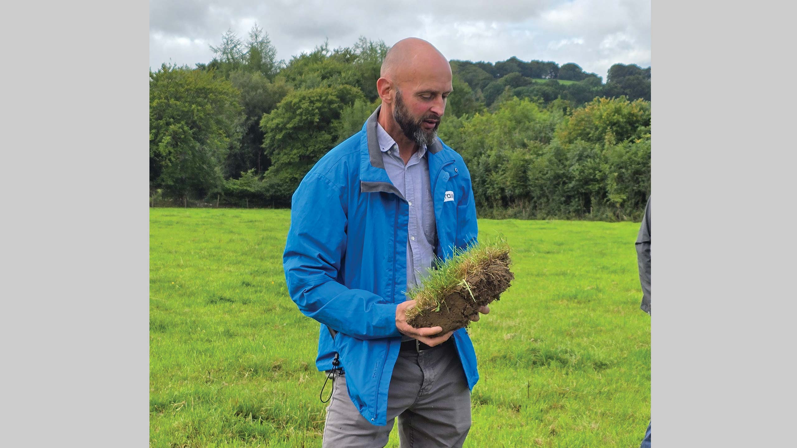 Man in a field holding a sod of grass