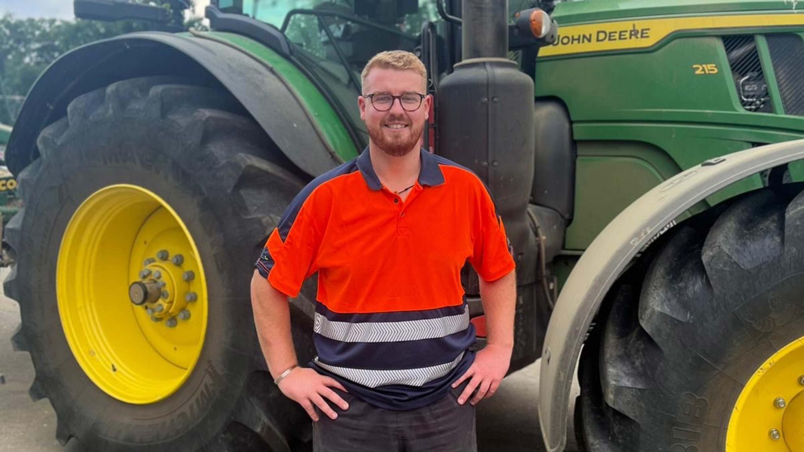 Farmer stands in front of a tractor