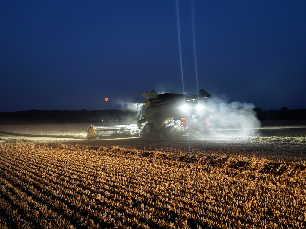 Harvesting at night with Sturgeon Moon in distance