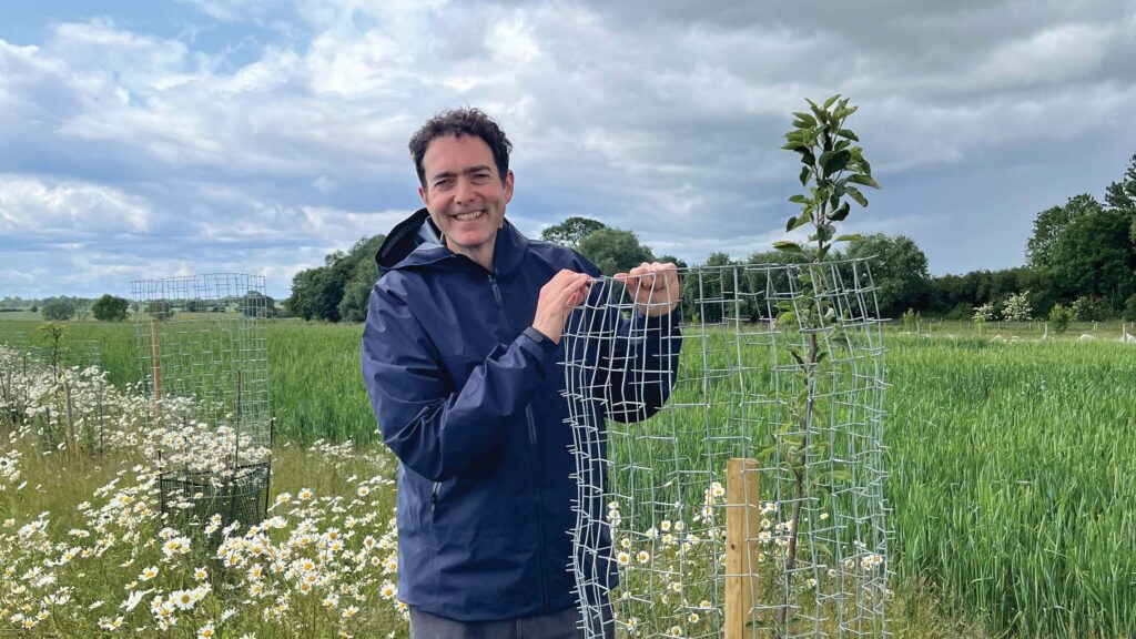 Farmer standing beside a newly planted tree