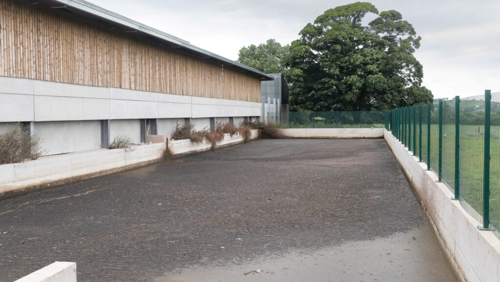 Open slurry pit beside a barn