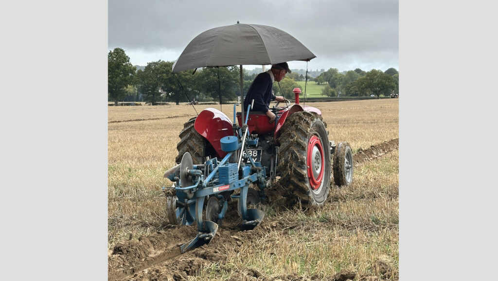 Umbrella 'roof' over farmer and vintage tractor
