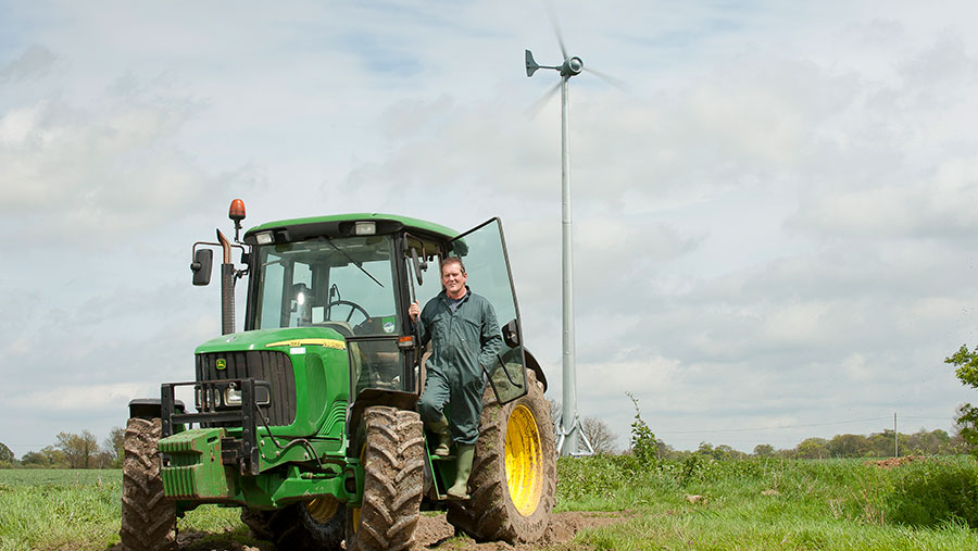 Man stood by tractor with wind turbine in background