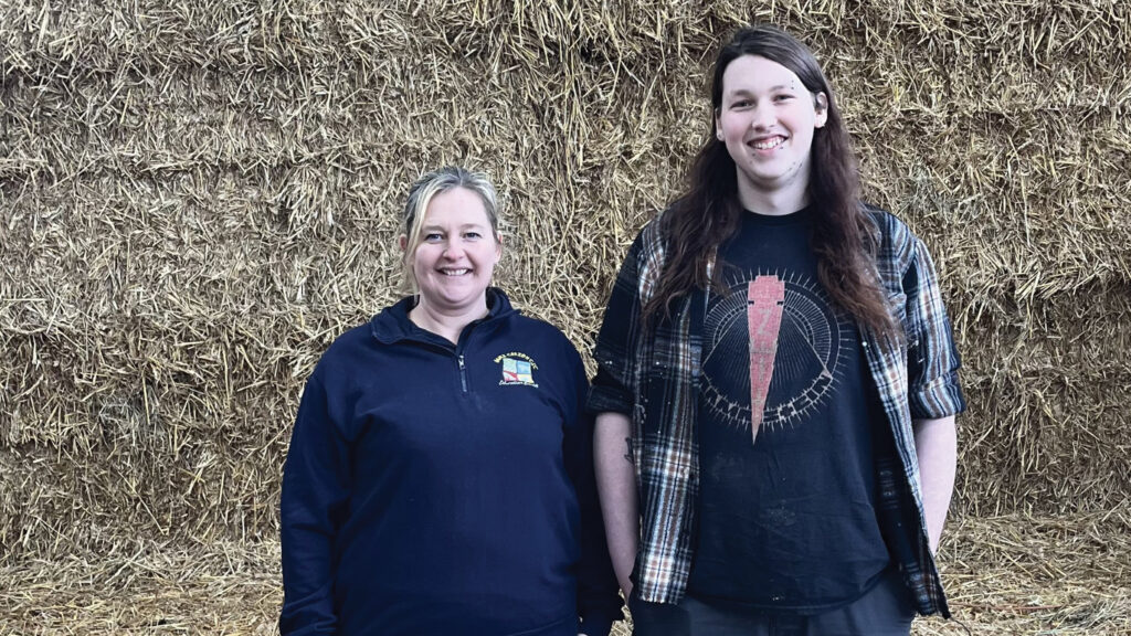 Two people pose in front of silage clamp