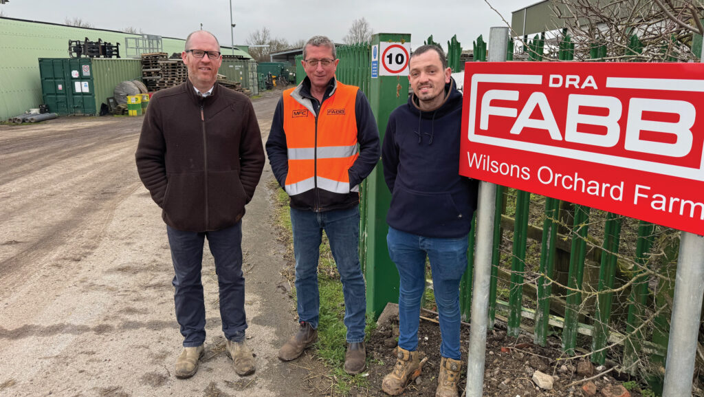 Three men stand beside a business sign
