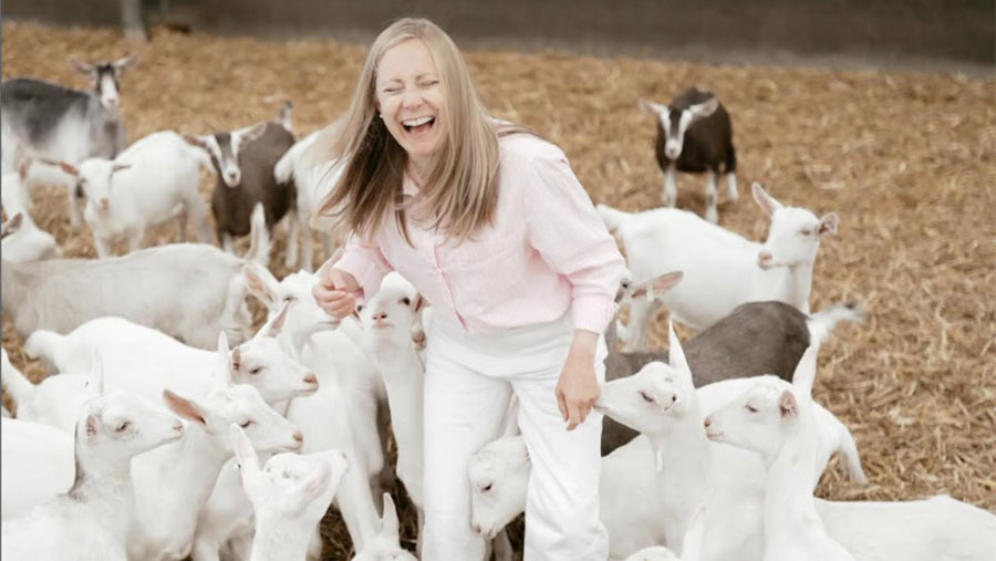 Person laughing whilst stood with group of goats