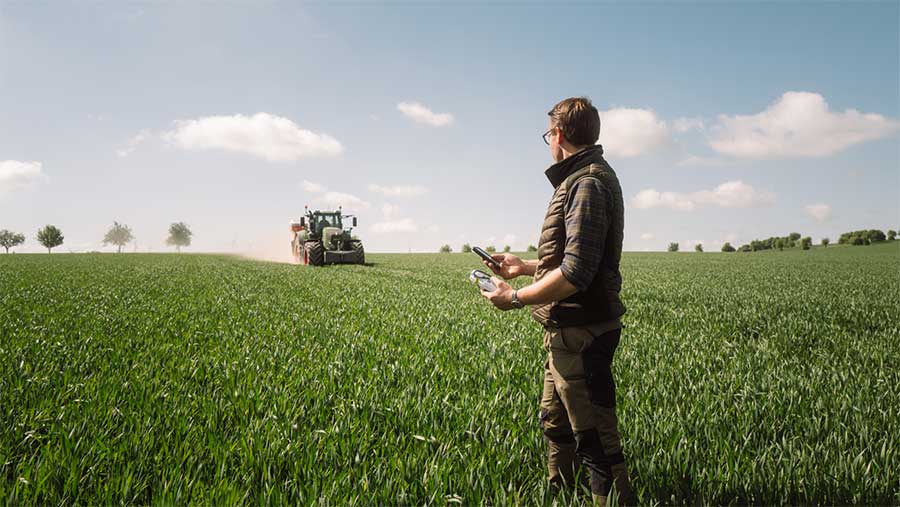Man stood in field looking out towards a tractor