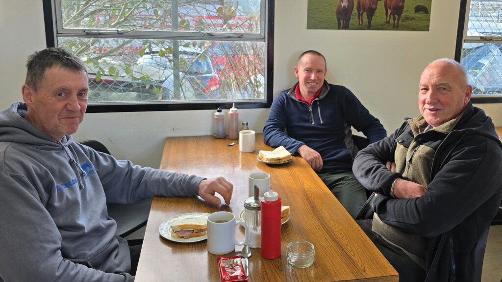 Three men sit at a cafe table