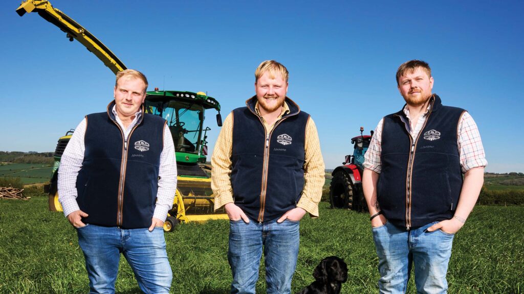 Three men pose in a field